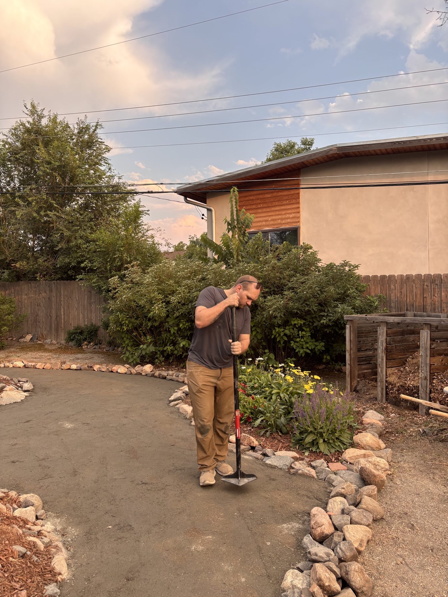 Tamping down the edge of the finished path, with the flower beds in bloom alongside it.