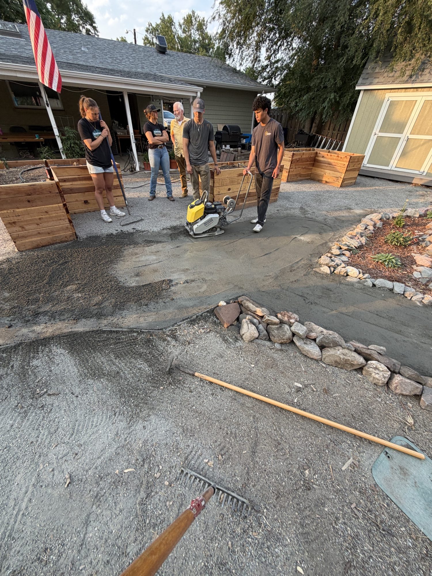 Running the plate compactor down the new path while the rest of the crew watches the grade.